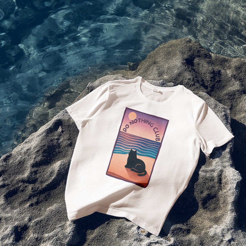White t-shirt with a graphic design on a rock by the water
