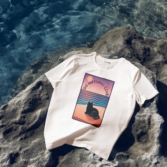 White t-shirt with a graphic design on a rock by the water